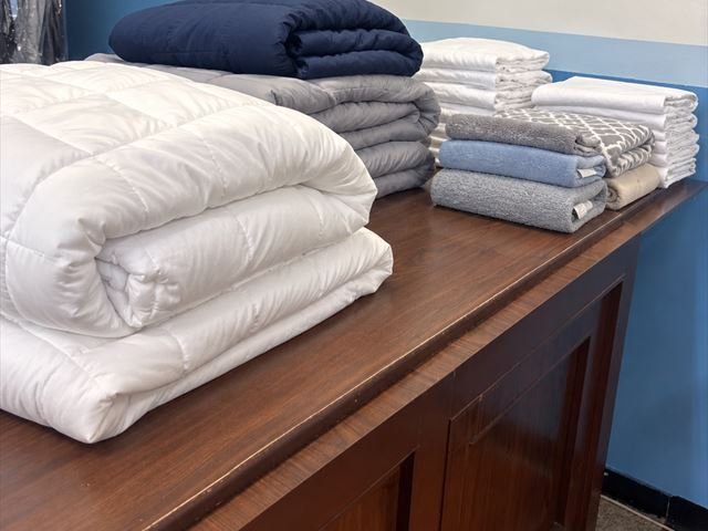Cleaned comforters, blankets and towels folded and stacked on the shop counter.