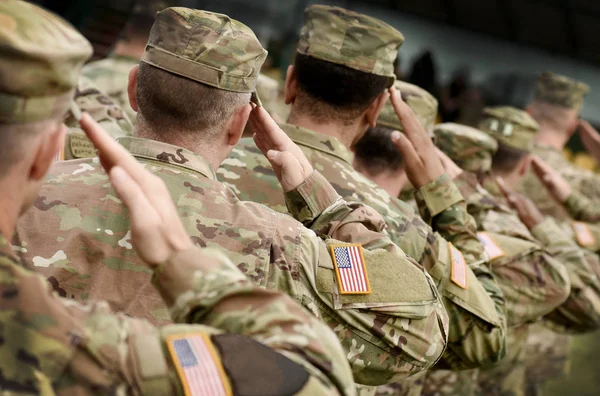 Soldiers in uniform saluting, the flag patch on each sleeve.